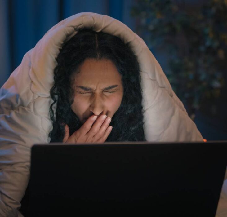 Tired Hispanic girl exhausted sleepy woman fatigued Indian Arabian female at night evening home couch sofa under blanket cover duvet working with laptop watching movie computer addict yawn need sleep. High quality 4k footage