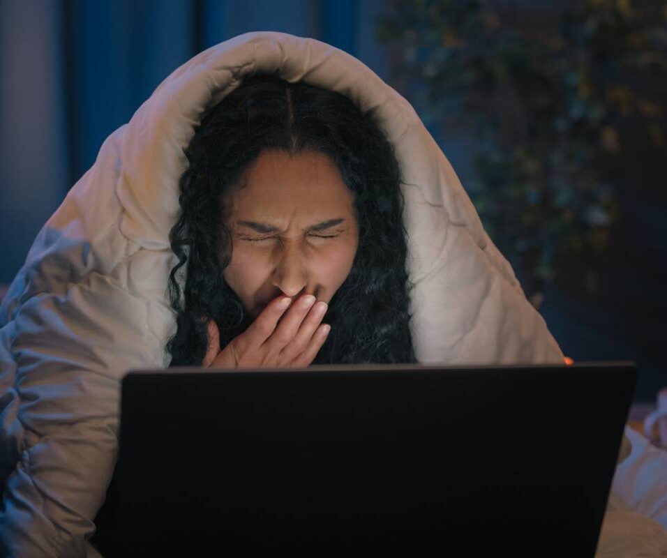 Tired Hispanic girl exhausted sleepy woman fatigued Indian Arabian female at night evening home couch sofa under blanket cover duvet working with laptop watching movie computer addict yawn need sleep. High quality 4k footage